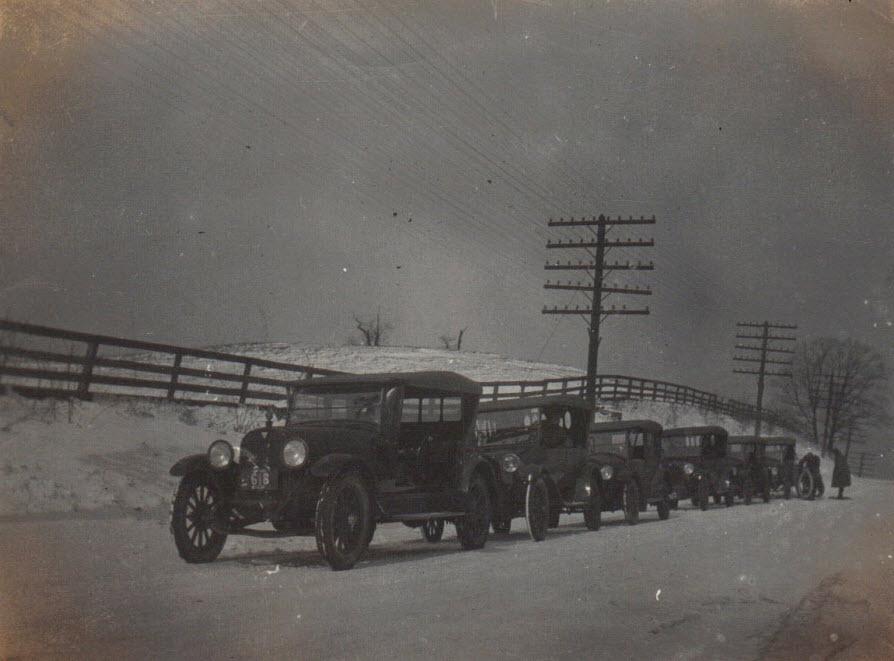Line of dealer cars on snowy road